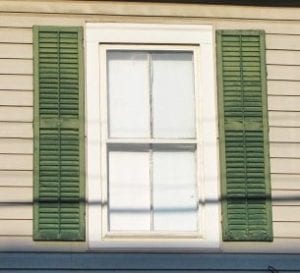 real wood shutters mounted next to window casing